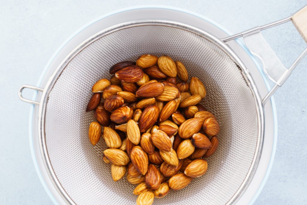 Soaked almonds in a strainer. Ingredients for nut milk.
