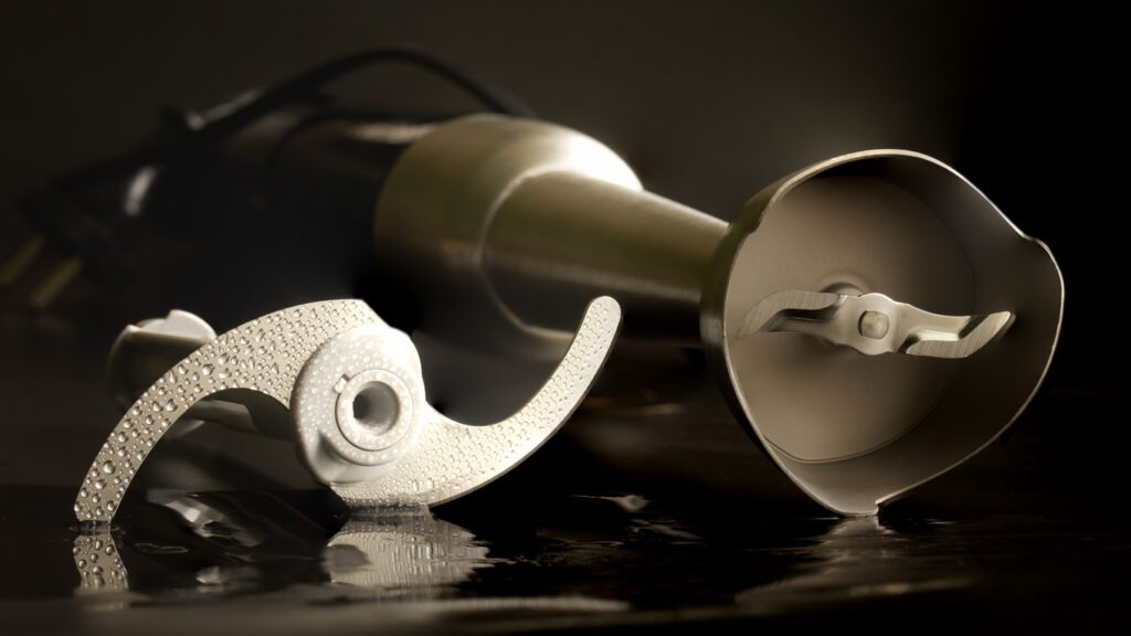 metal-whisk-and-steel-blade-of-a-hand-blender-on-a-damp-surface-macro