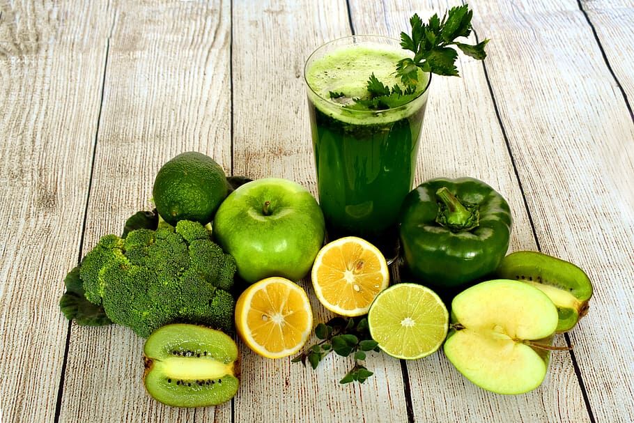 Green smoothie surrounded with various vegetables and fruit