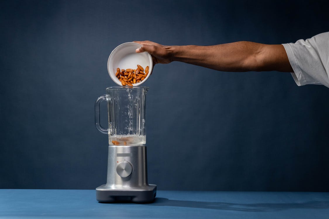 person adding almonds in a blender