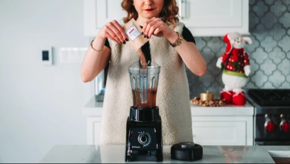 a woman putting ingredients in a blender