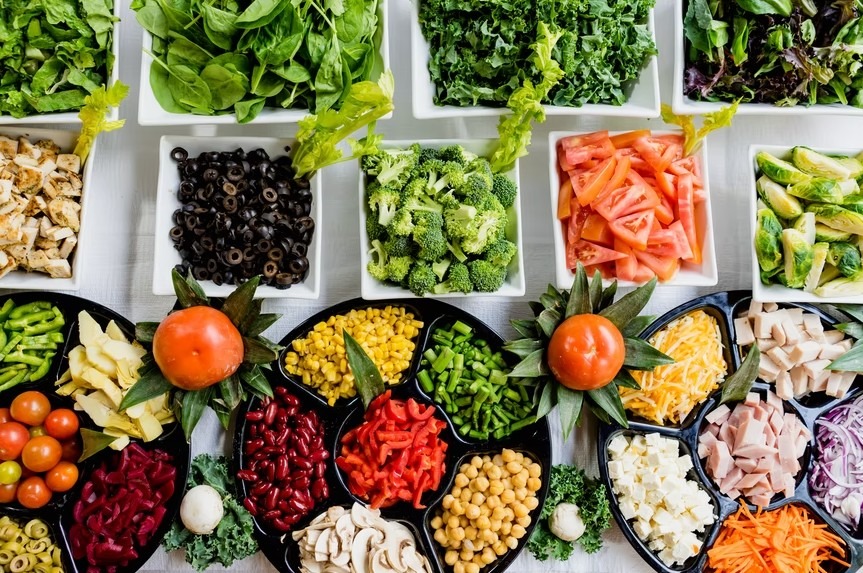 various raw foods, including vegetables, lentils, and leafy greens in several bowls