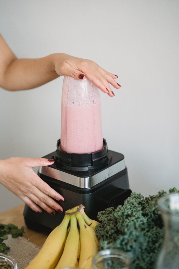a person making strawberry smoothie using blender